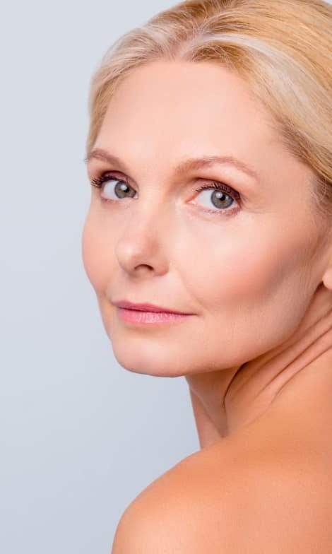 Woman with clear, even skin looking over her shoulder
