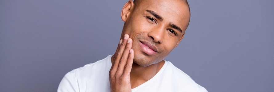 portrait of a man with his hand on his face after men's skin care treatment